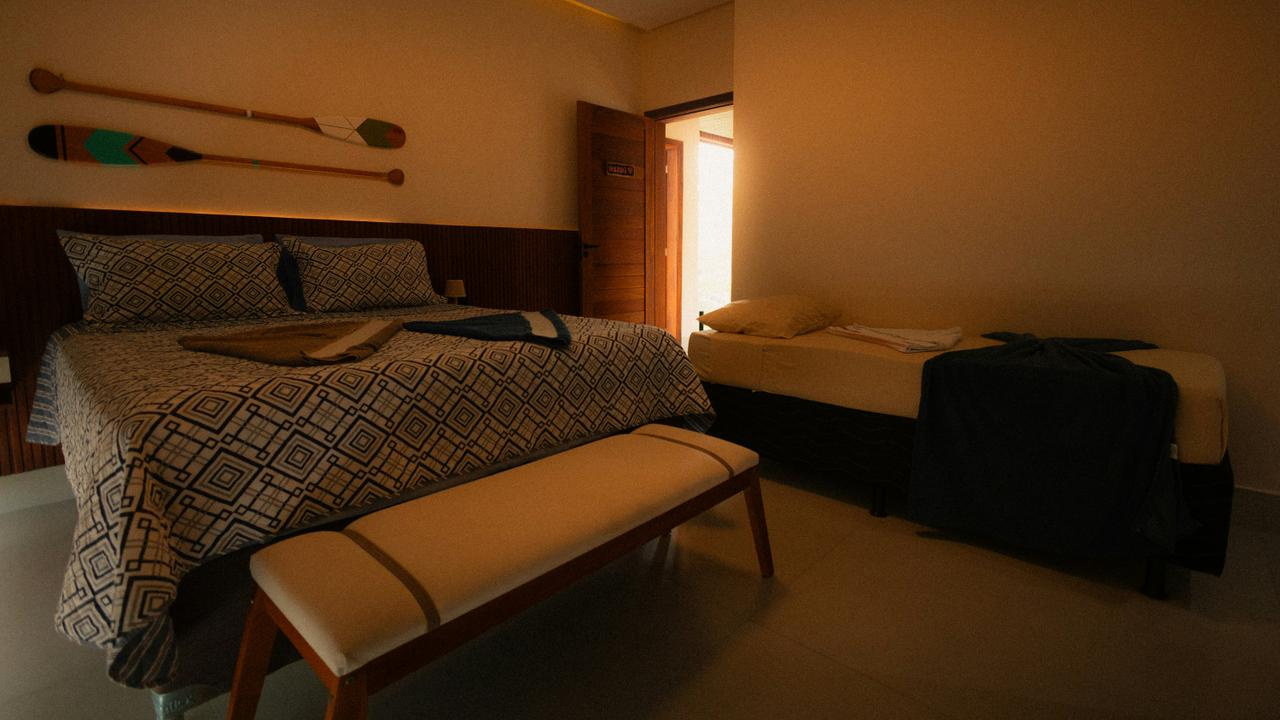 Spavaća soba sa velikim krevetom, klupicom i veslima na zidu Spavaća soba sa velikim krevetom, klupicom i veslima na zidu